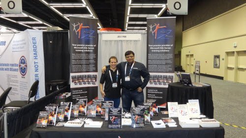Two people stand behind booth displaying informational material.