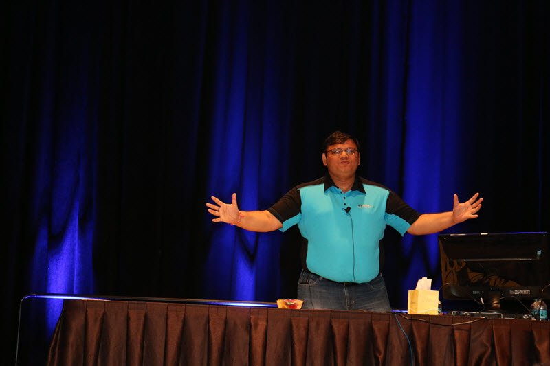 A man gestures while giving a presentation.
