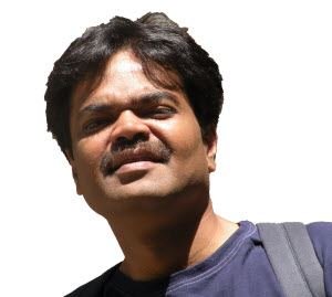A man with a mustache and dark hair is smiling.